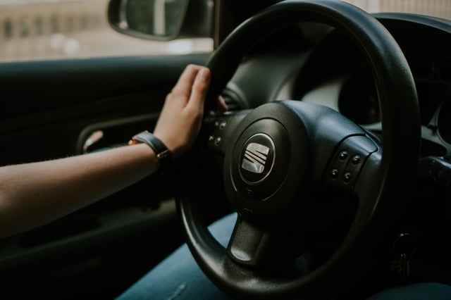 Iemand houdt het stuur van een personenauto vast