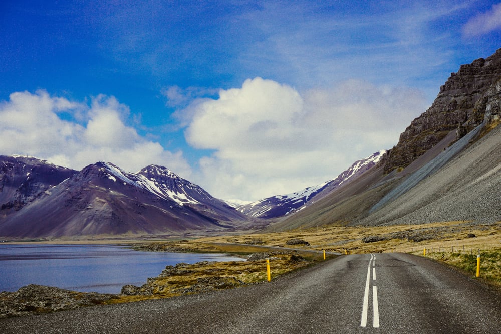 Weg tussen een meer en bergen in IJsland