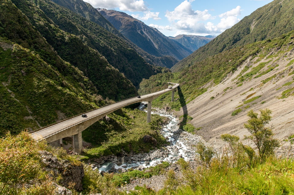 Auto's op het gebogen Otira-viaduct boven een rotsige rivier in de bergen van Arthur's Pass, Nieuw-Zeeland.